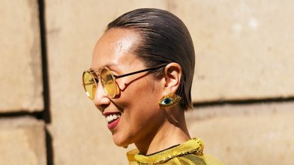 side profile of a woman with slicked back hair smiling on a city street
