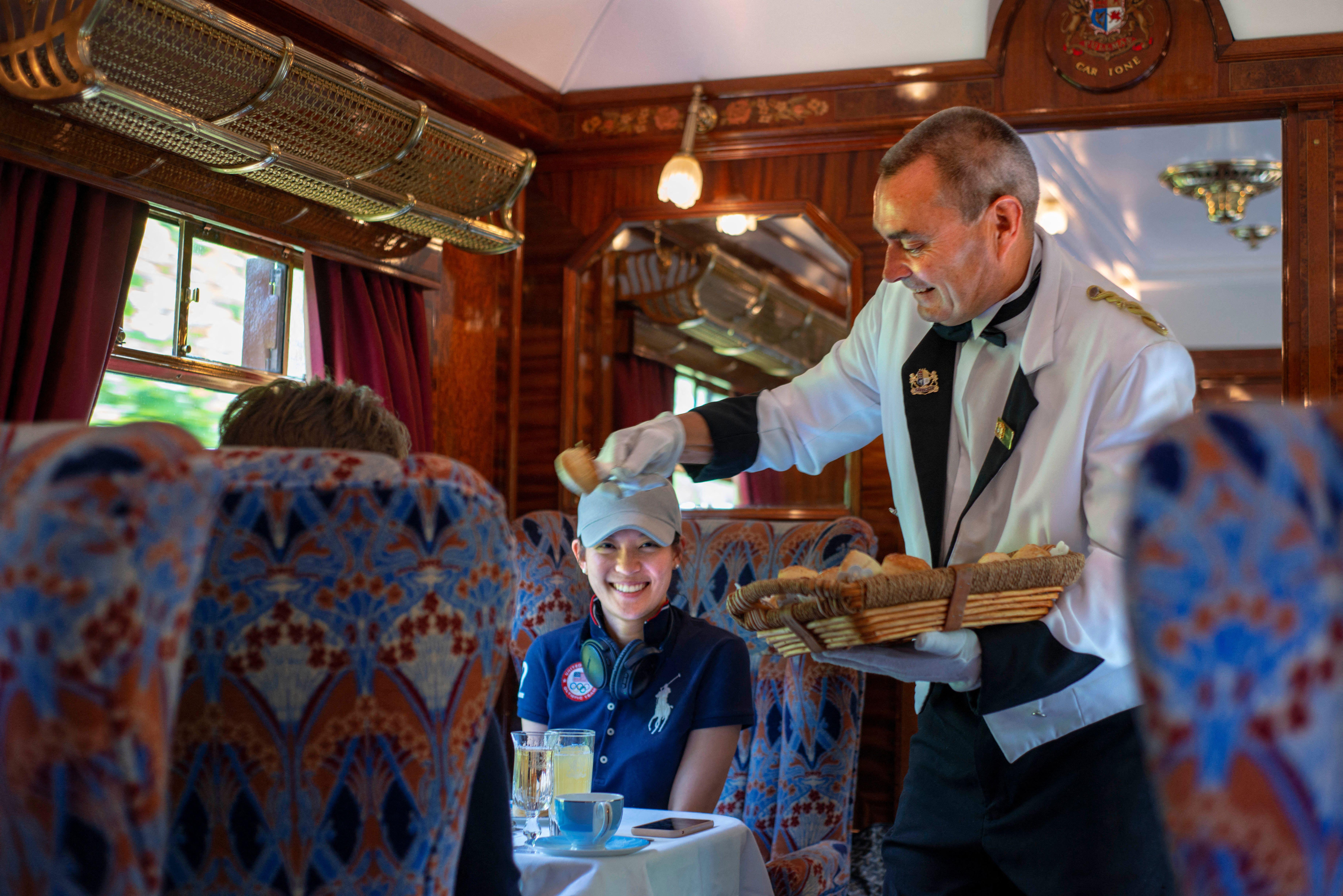 A waiter serves the lunch inside the restaurant wagon of the train Belmond British Pullman