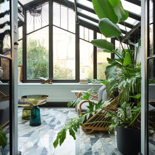 Conservatory with dark grey frames, grey marbled floor and lush foliaged plants