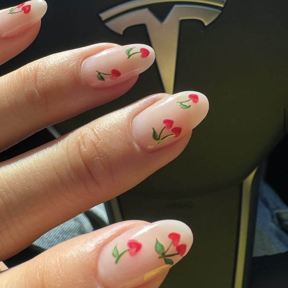 A nude manicure with cherry heart detailing.