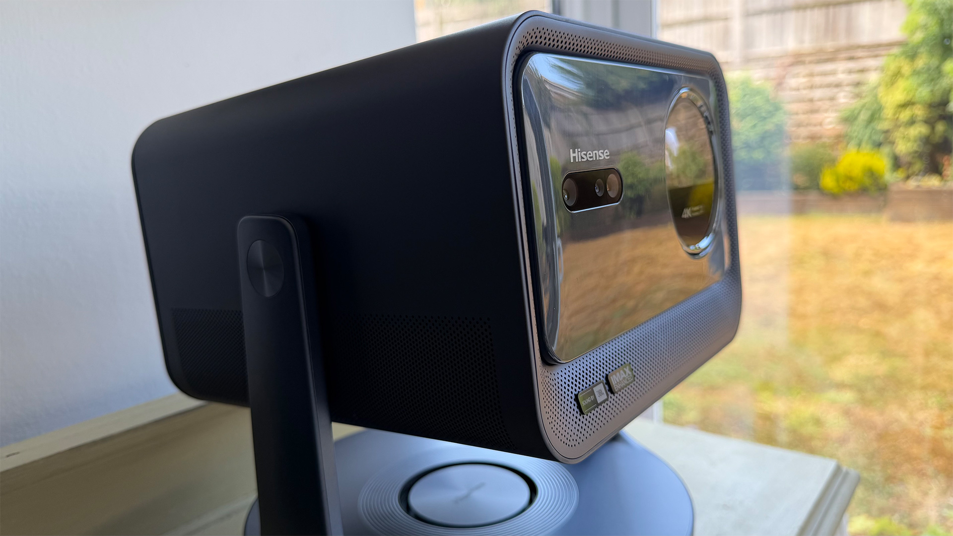 Hisense C2 Ultra home cinema projector from right hand side, behind is garden seen through window