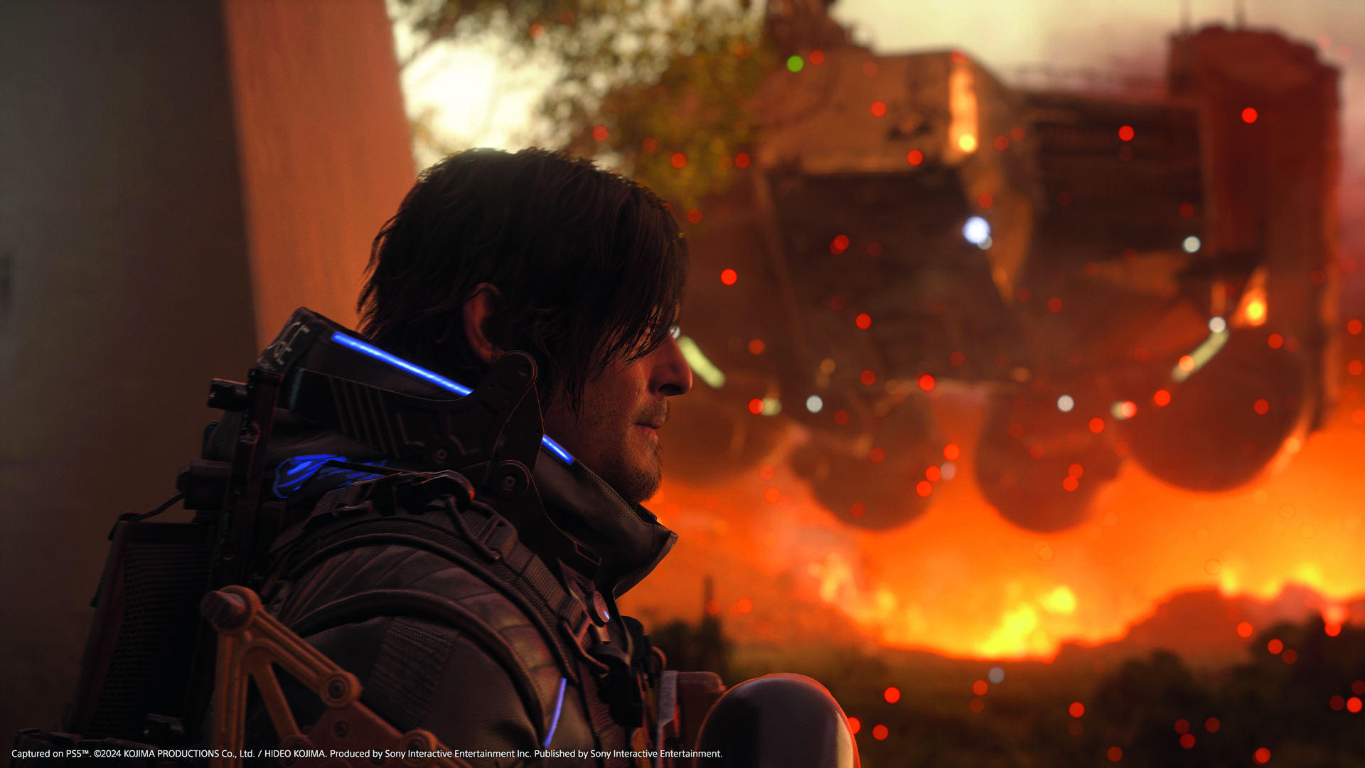 Sam Bridges stands in front of a flying ship with fire below it in Death Stranding 2: On the Beach, from the Edge Magazine cover feature
