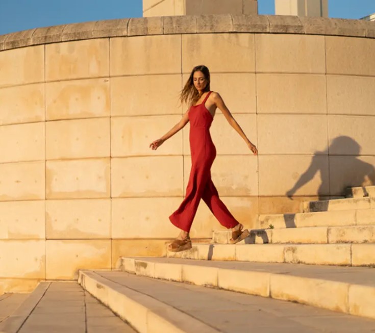 A woman walking down outdoor steps in a red jumpsuit