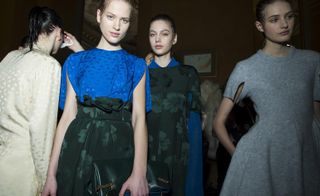 Models wearing blue, green, cream and grey dresses