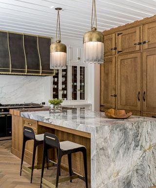 Sabah Mansoor kitchen with wood cabinet doors, marble island and brass pendant lamps