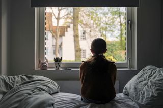 Image of a woman looking outside her window
