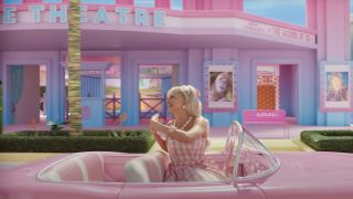 Margot Robbie's Barbie waving while driving by movie theater