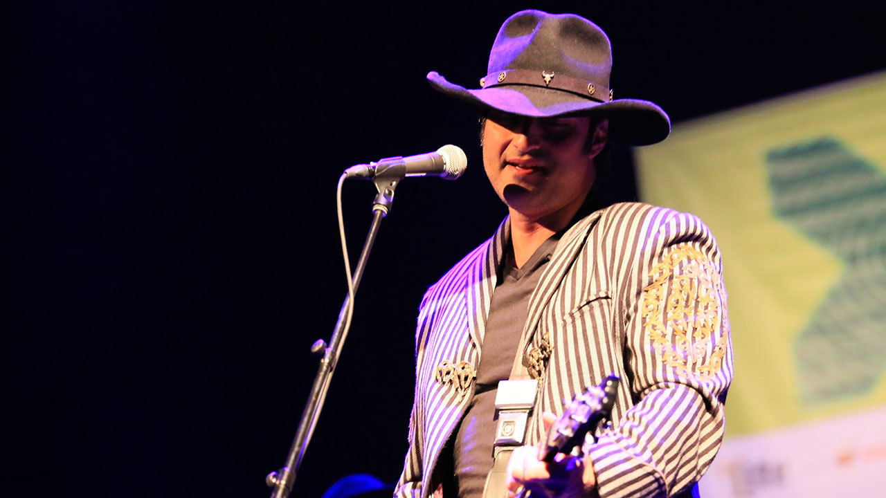 A photograph of Robert Rodriguez on stage with his band Chingon