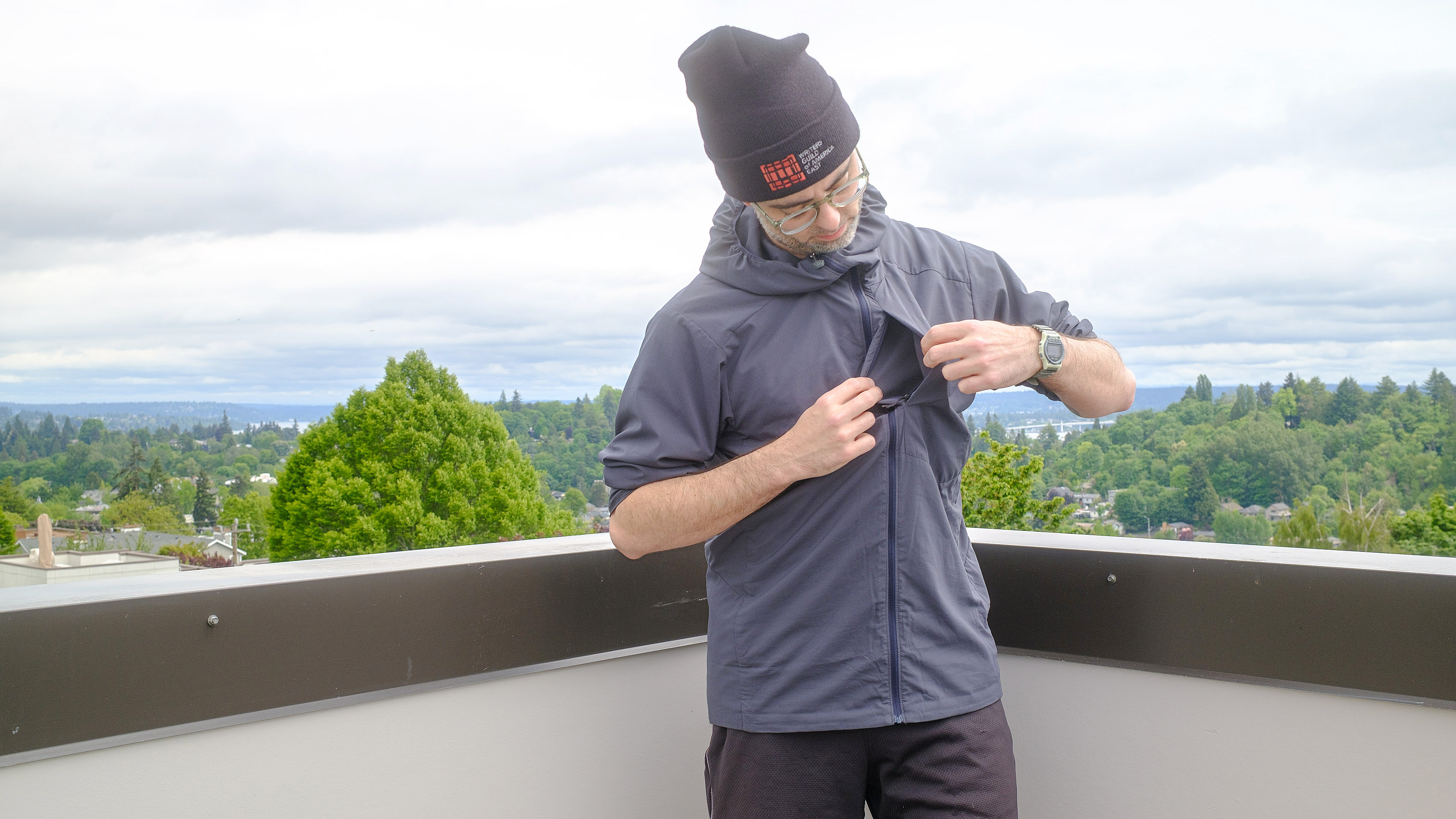 Senior writer Dan Bracaglia wearing the Patagonia Nano-Air Ultralight in grey/blue on the roof of his home in Seattle, Washington with trees and overcast skies in the distance