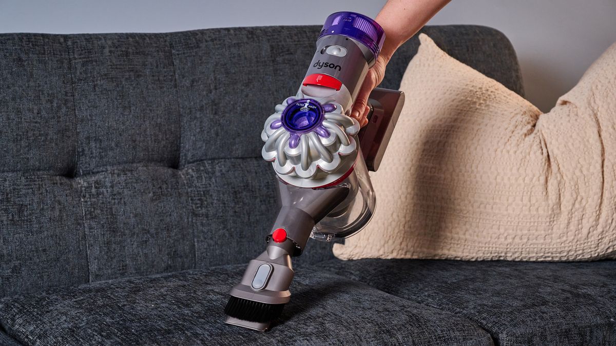 Person using the Dyson Car+Boat handheld vacuum on a sofa
