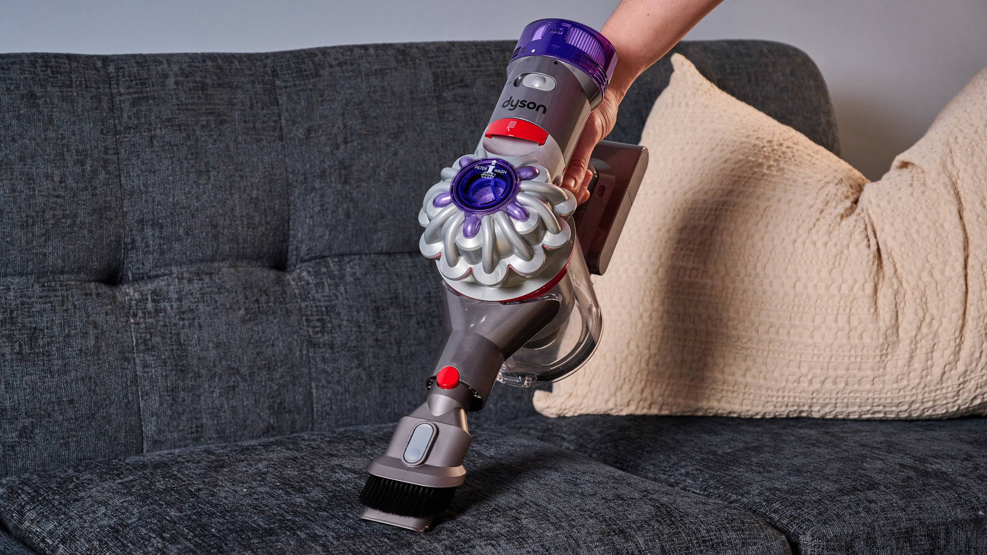 Person using the Dyson Car+Boat handheld vacuum on a sofa