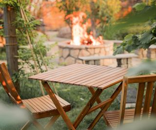 A fire pit in the background of a wooden patio set