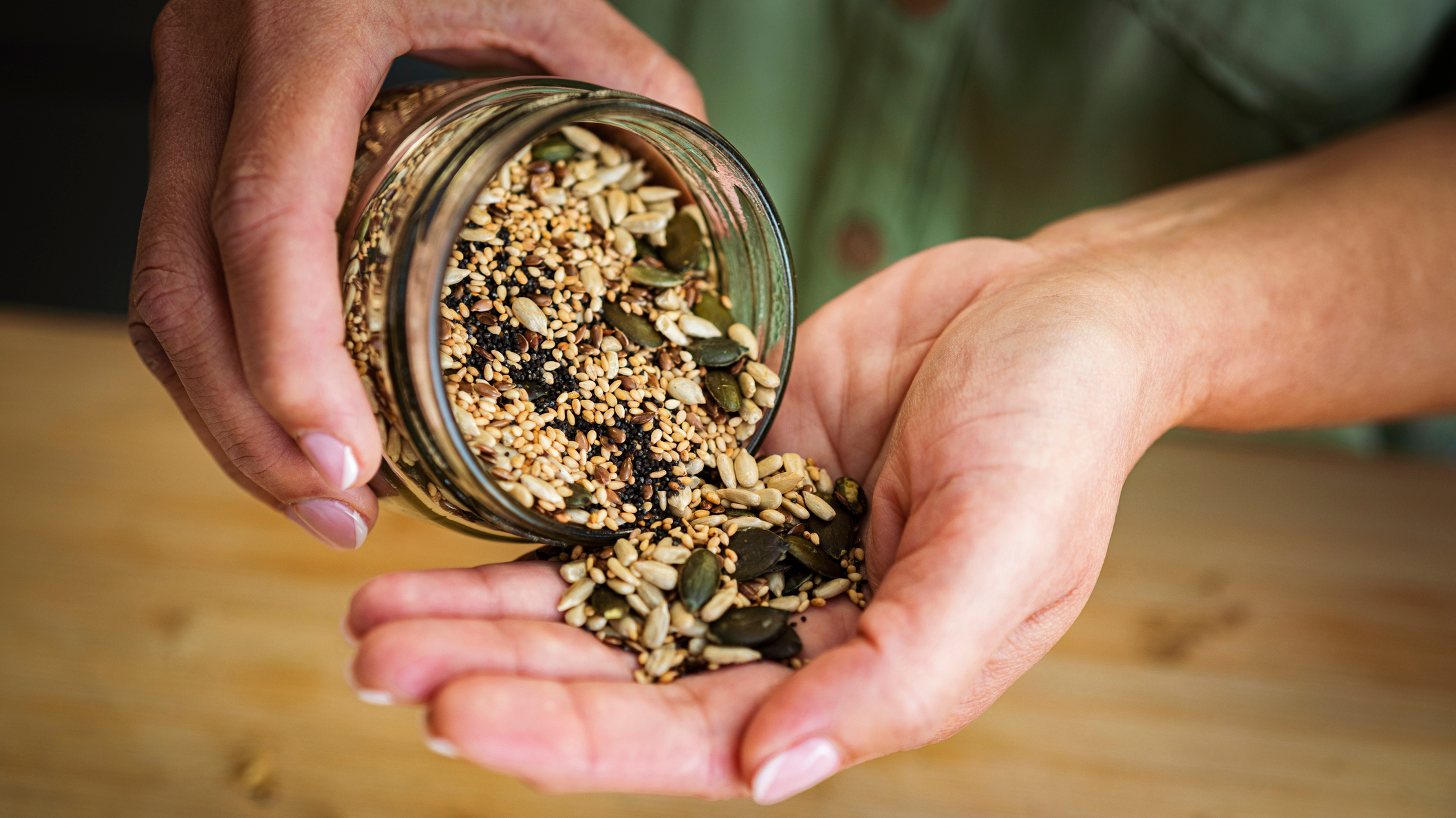 Close-up of a jar of seeds pouring into a cupped hand