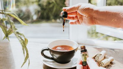 Person dripping CBD oil into a coffee