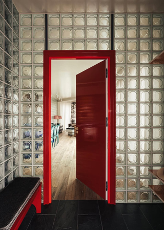 A glass block wall with a red door