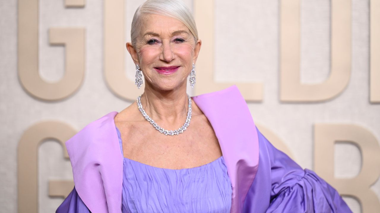 Helen Mirren at the Golden Globe Awards, wearing a purple outfit and large diamond earrings and necklace