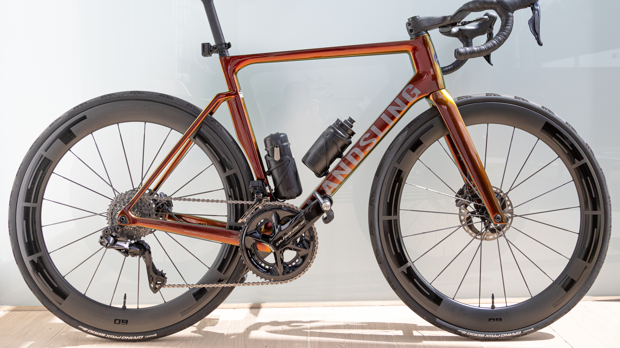 an orange Handsling road bike with 60mm deep carbon wheels against a white background
