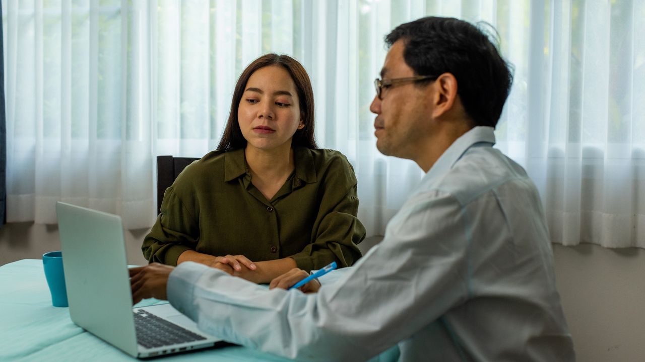 A financial adviser works with a client at her table at home.