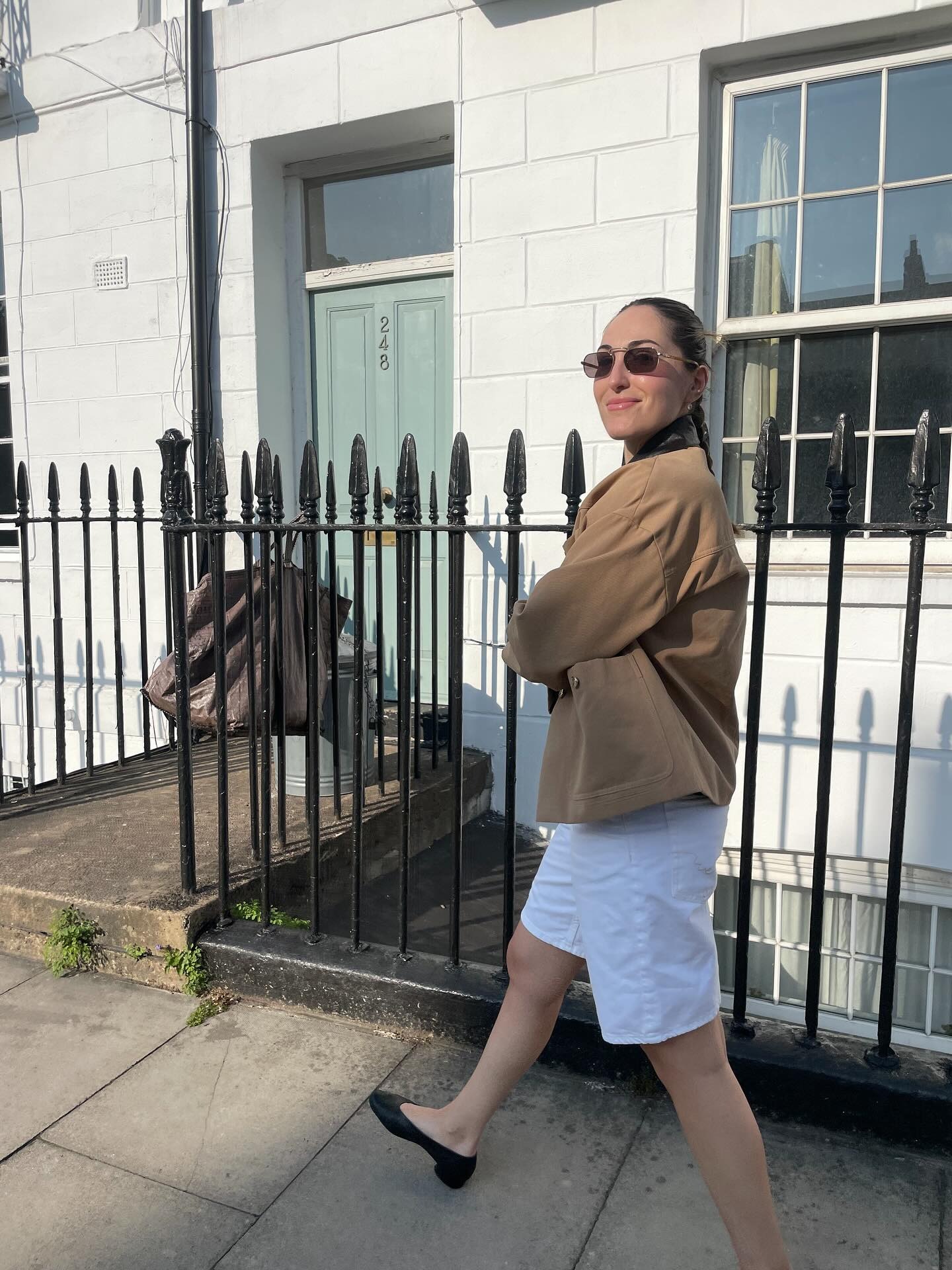 a woman wearing a barn jacket with long white shorts and pumped