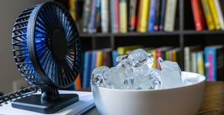 a small desk fan behind a bowl of ice to show how to cool down a room without ac