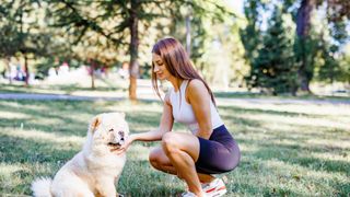 Woman squatting next to dog