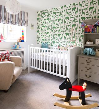 nursery with green zoo print wallpaper feature wall