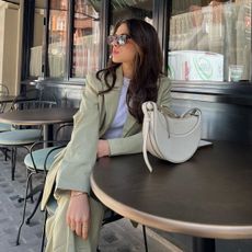 @tia_dewitt wears a sage-green suit with a cream bag