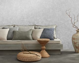 In front of a white wall is a low sofa with a concrete base and sustainable upholstery, along with selected cushions
