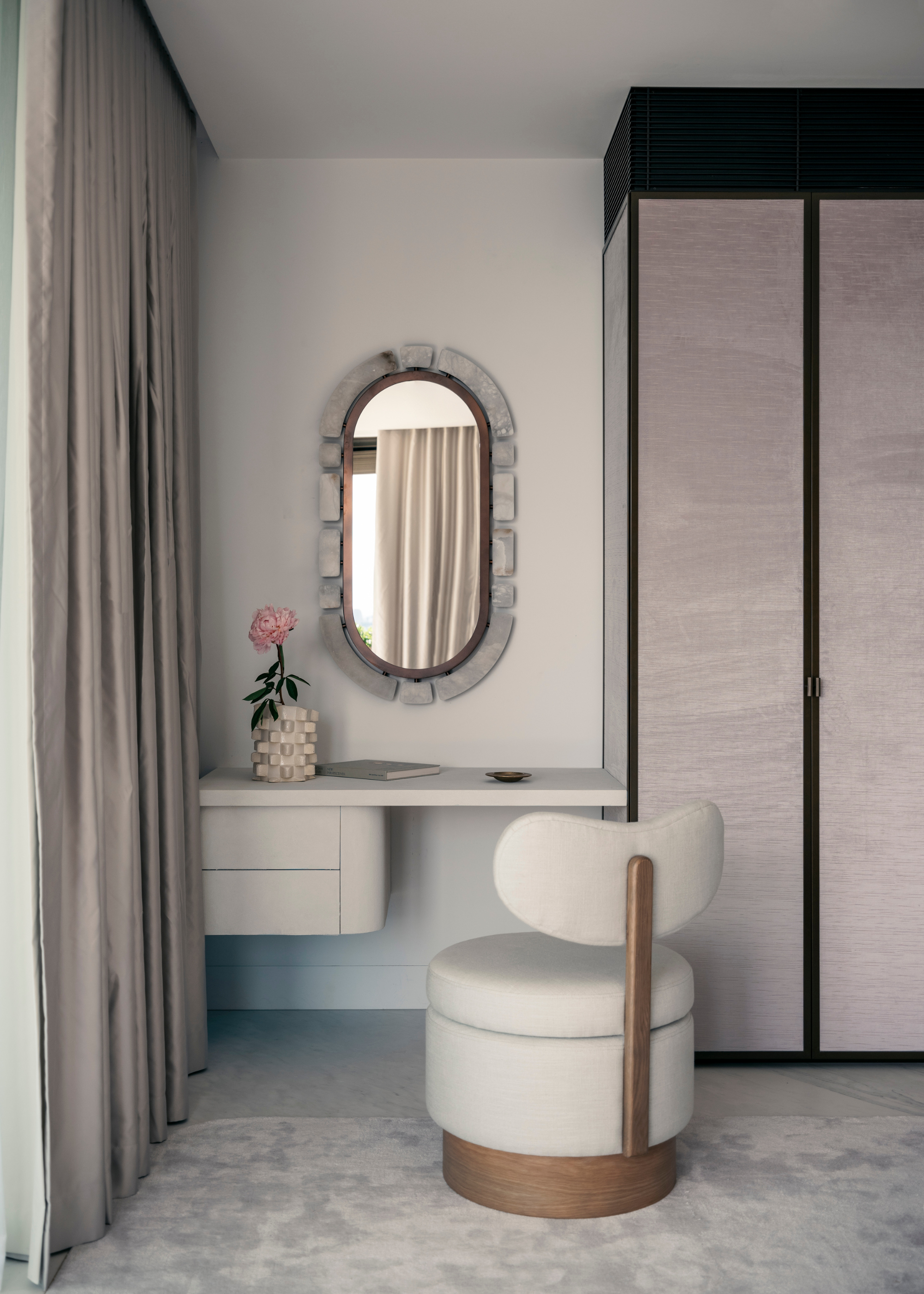 A minimalist bedroom beside gray cupboard, a white floating vanity with a swivel stool and a curved mirror