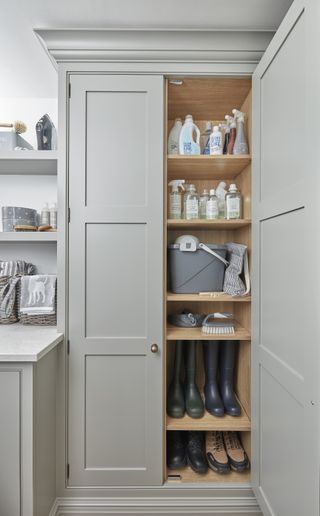 cupboard with cleaning products in a laundry room with wellies