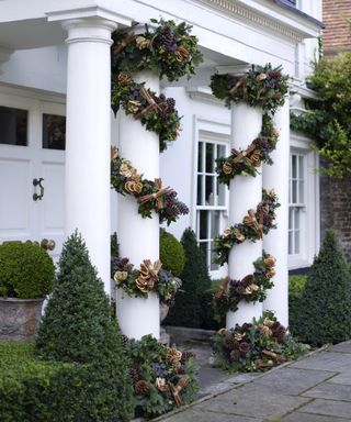 Christmas porch decor ideas with garlands wrapped around white columns