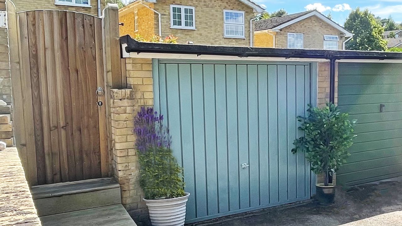 Blue painted garage door with purple flowers surrounding