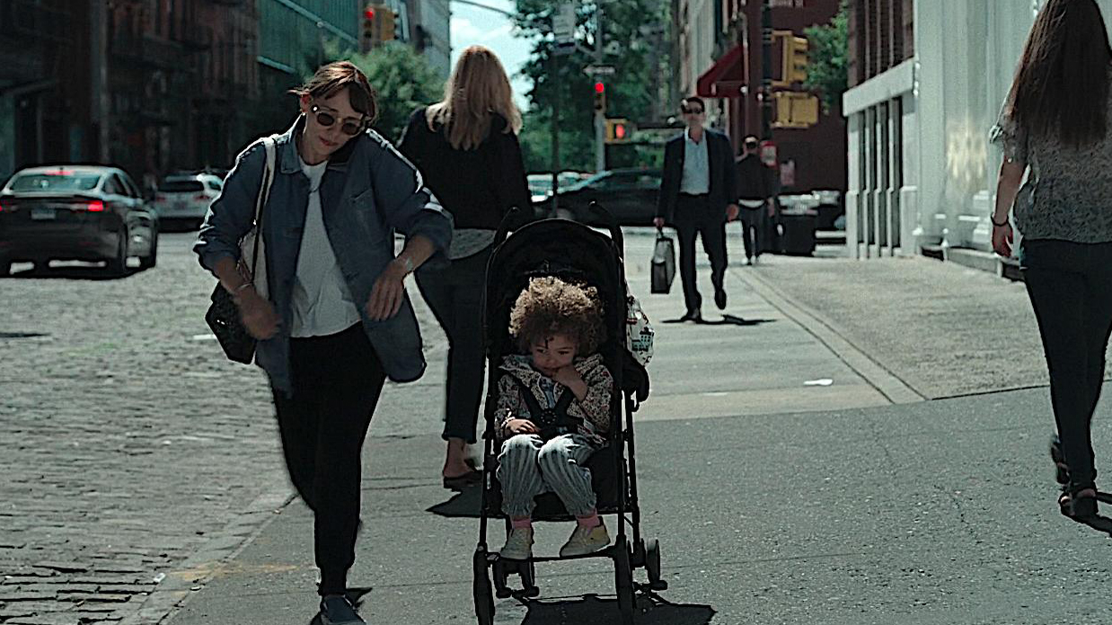 On The Rocks masih dari film – wanita berjalan di samping seorang anak di kursi dorong