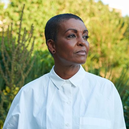 Adjoa Andoh wearing a white shirt in front of plants