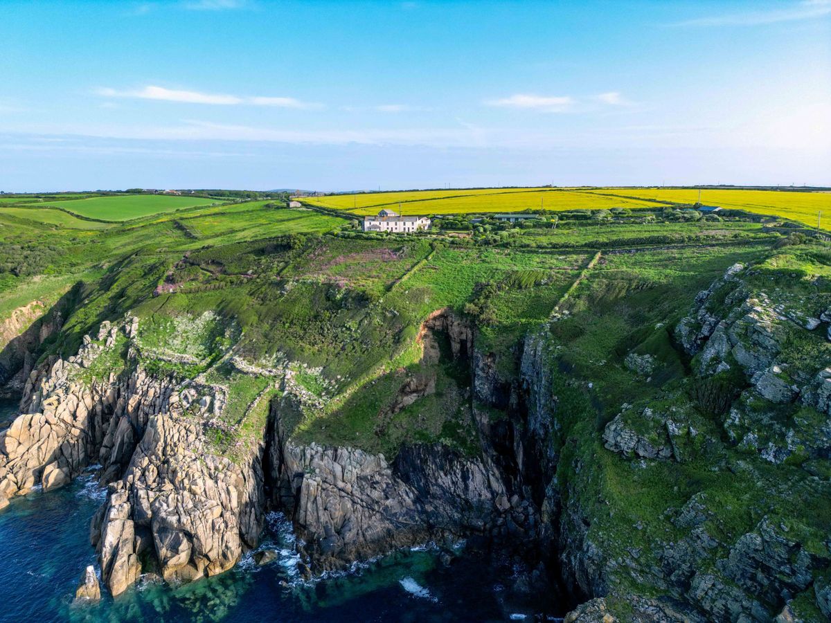 A house in the distant looking out over the sea completely on its own surrounded by fields