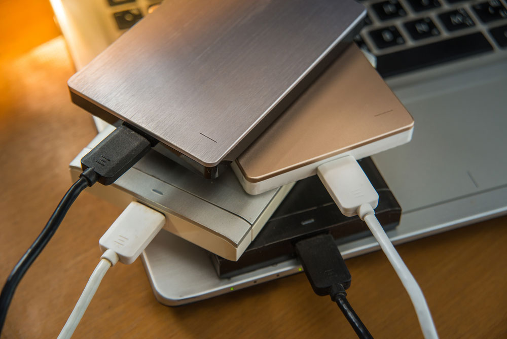 External hard drives stacked on top of laptop. Best cloud backup review