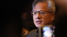 A close-up photo of Jensen Huang, CEO at Nvidia, with his head and shoulders visible and partially obscured by an out of focus phone screen.