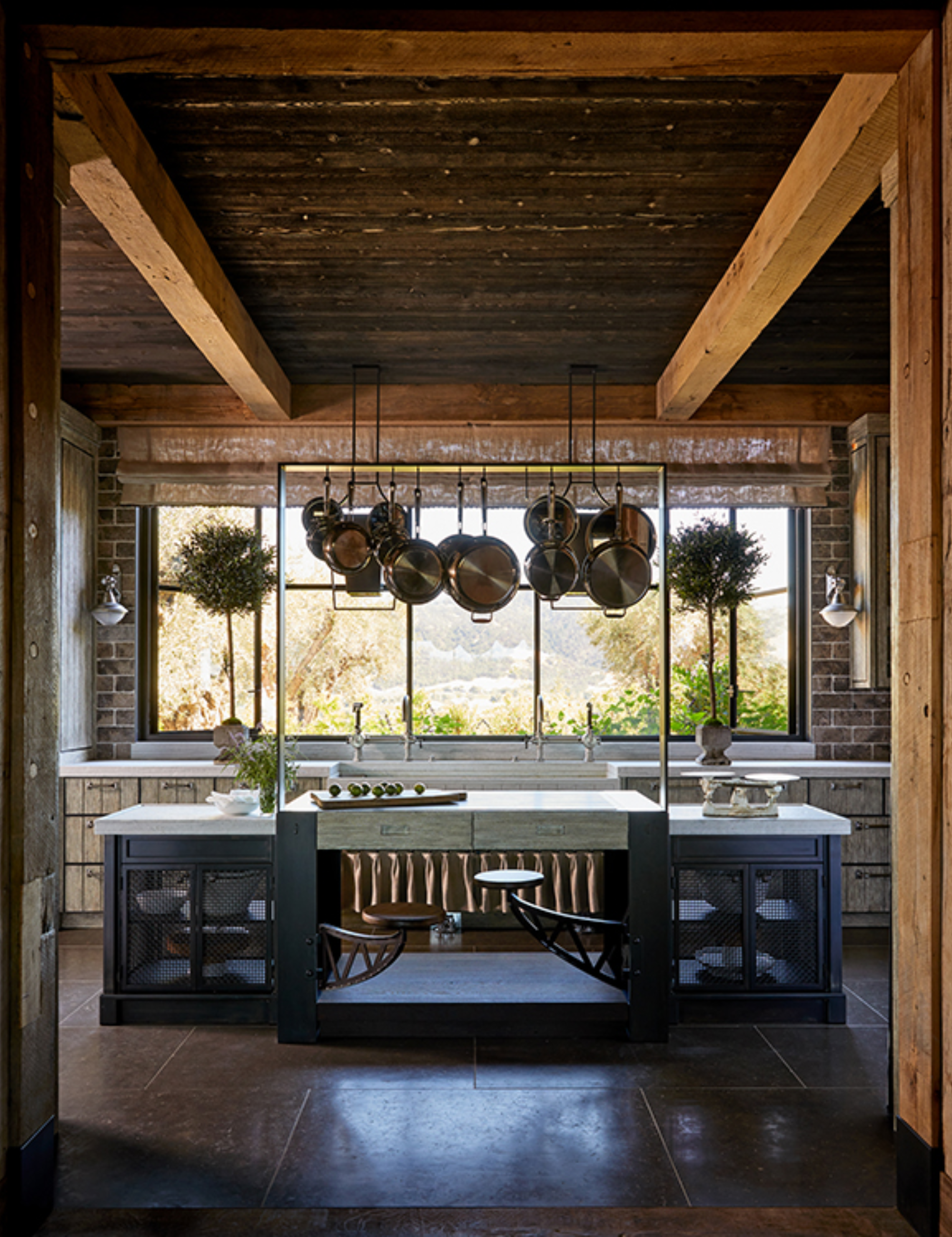 Equestrian-inspired kitchen brimming with rustic accents, including a copper-accented island, exposed wood beams, and aged iron fixtures.