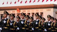 Chinese soldiers in dress uniform marching while holding rifles