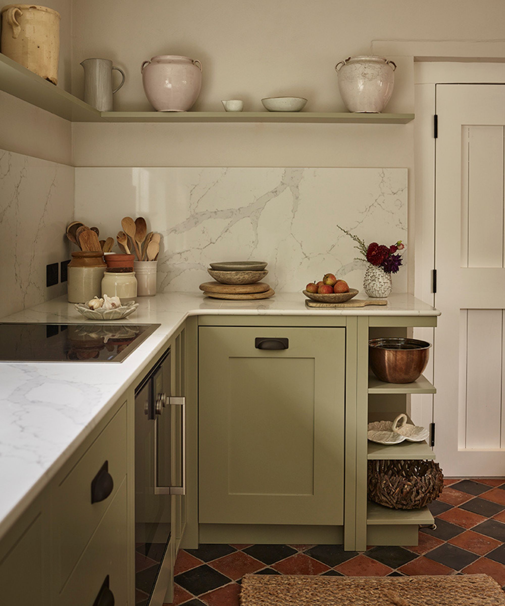 a pale green cottage kitchen corner with marble countertops and backsplash with orignal red and black quarry tiled floor