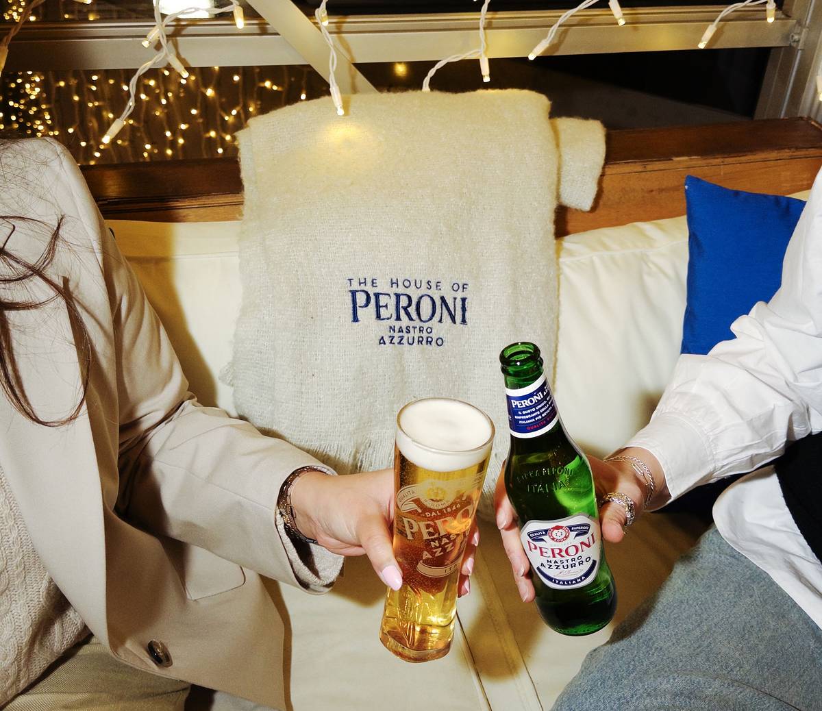 an image of two people cheers-ing a peroni pint and a peroni bottle in their glasshouse terrace on southbank