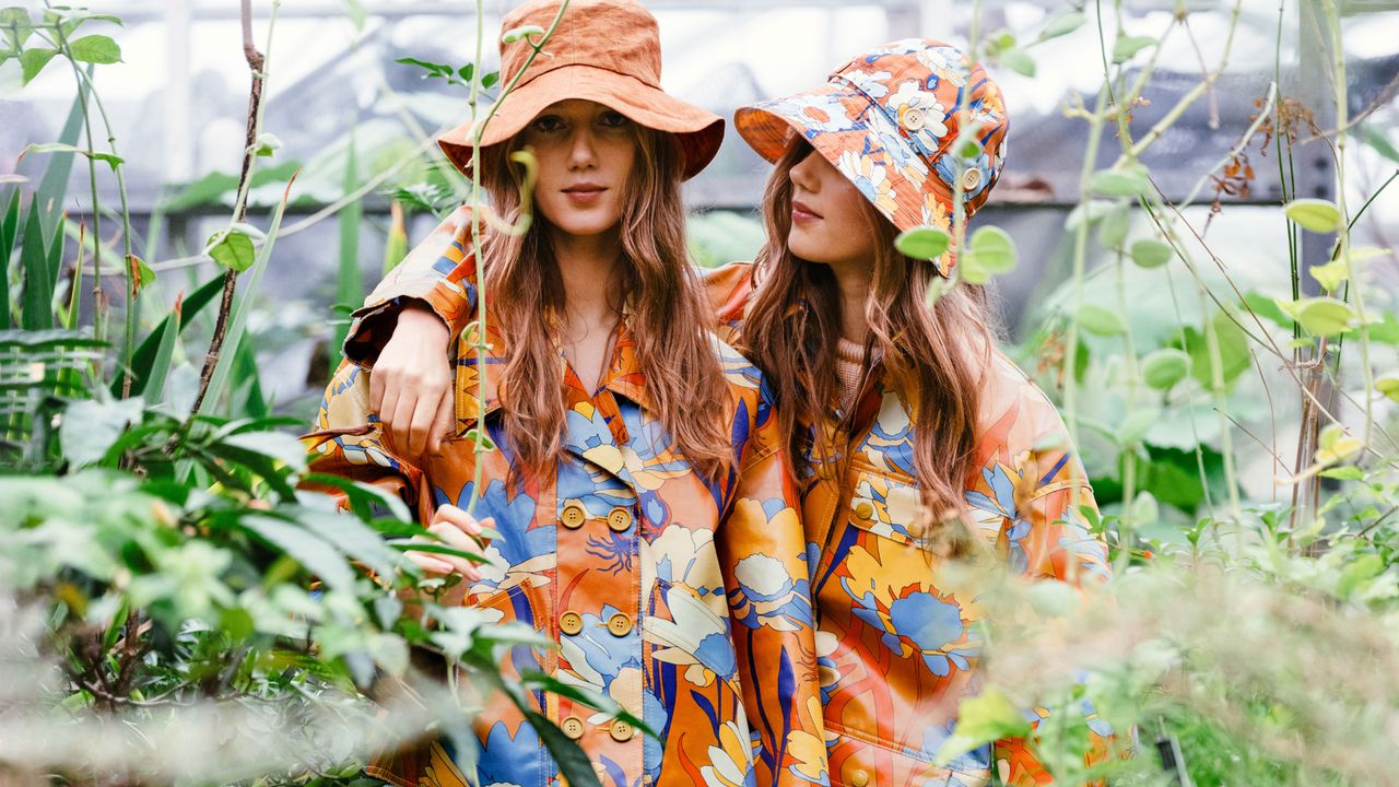 women in orange floral rain boots, jacket, hat, and skirt