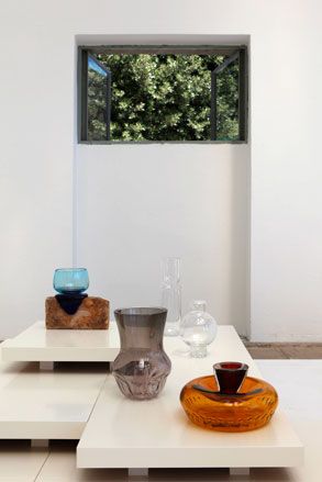 Contemporary glass designs photographed on white platforms with a window and white walls in the background