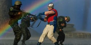 Peacemaker beats up soldiers with rainbow in the background The Sucide Squad