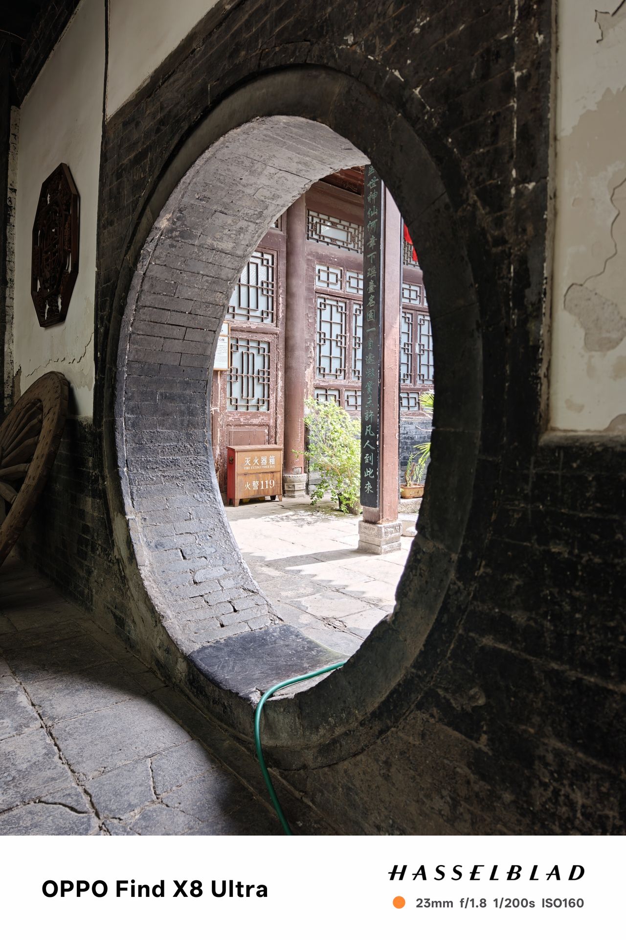 A circular hole in a wall leading into a Chinese courtyard