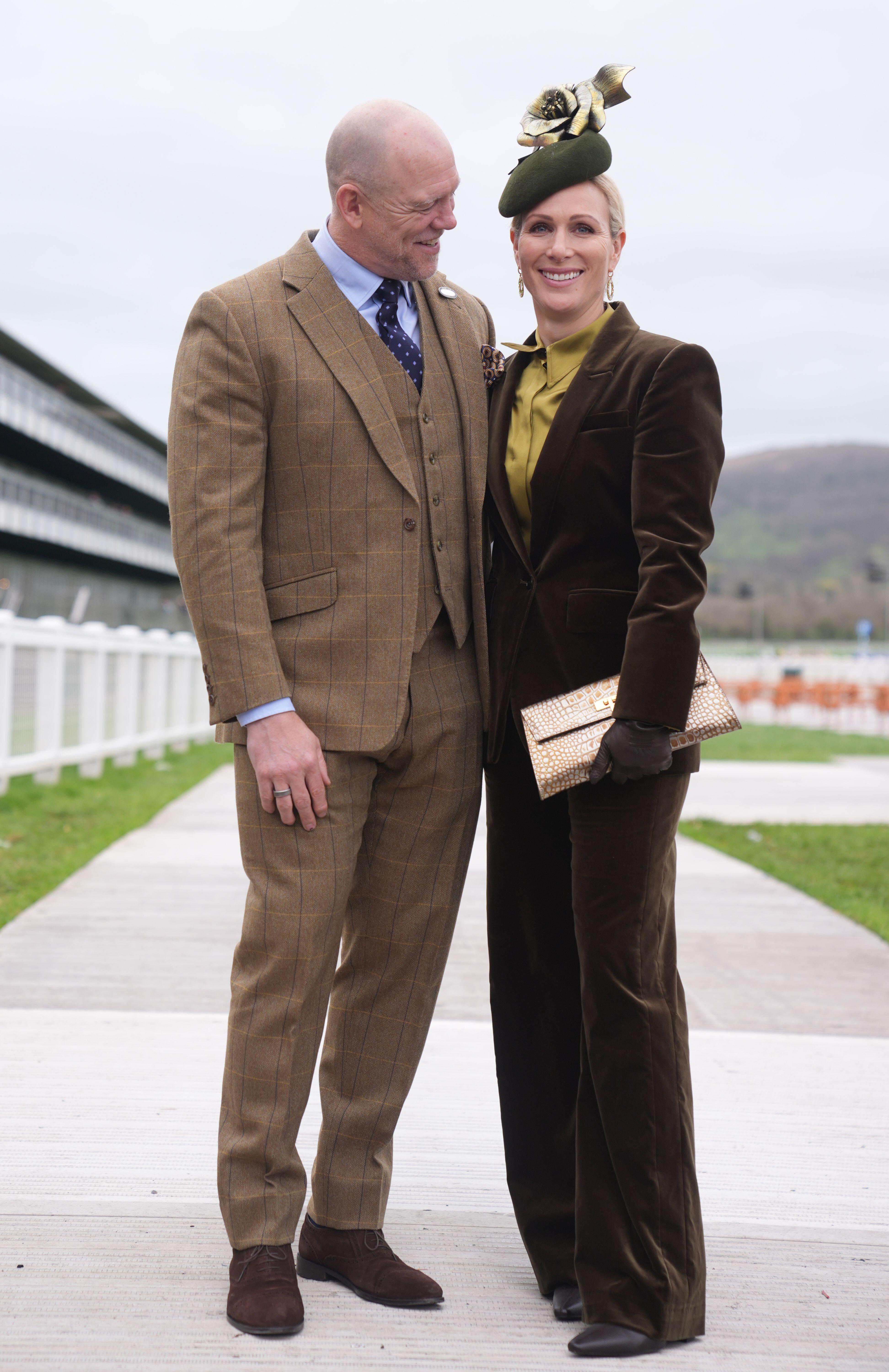 Mike Tindall in a brown suit smiling and looking at Zara Tindall, wearing a green suit
