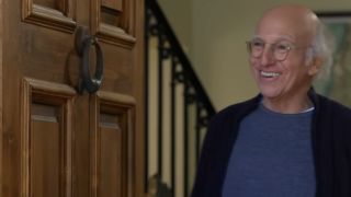 Larry David smiling in a doorway in Curb Your Enthusiasm