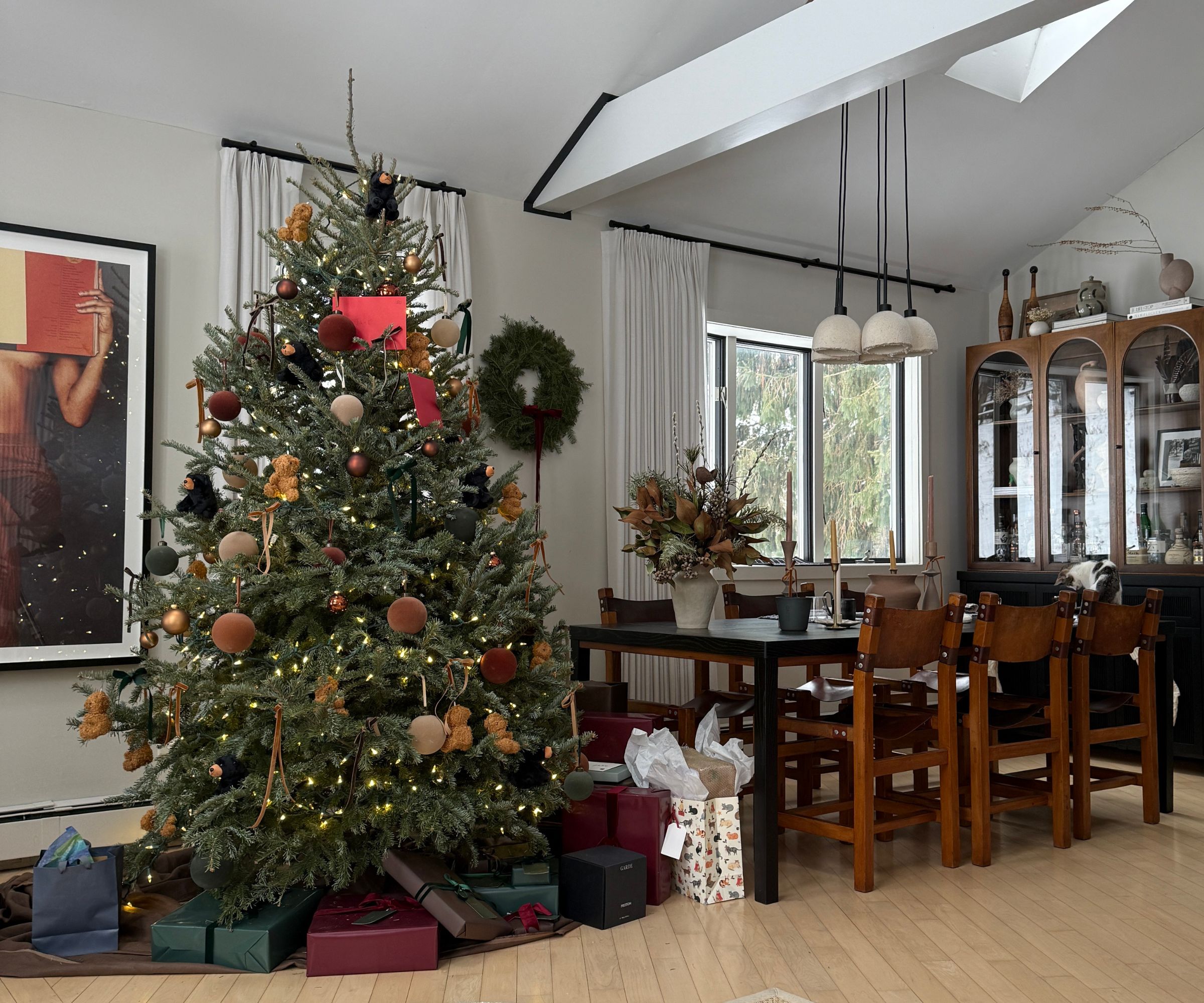 modern dining room with vintage chairs styled for Christmas with a large christmas tree, wreaths, and wrapped presents