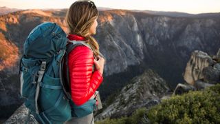 A female backpacking over rocky terrain during sunset