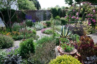 small garden on a hilltop with colourful borders and brick paths